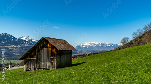 Eine alte Holzscheune, Heuschober oder Stadel in Düns, im Grossen Walsertal, mit Blick zum Rhätikon, Alpstein und Säntis. blauer Himmel und verschneite Bergspitzen.