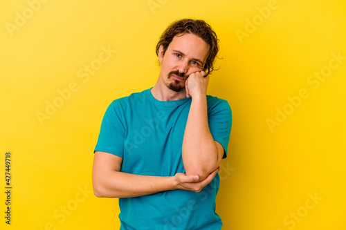 Young caucasian man isolated on yellow background tired of a repetitive task.