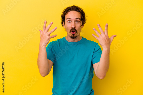 Young caucasian man isolated on yellow background showing number ten with hands.