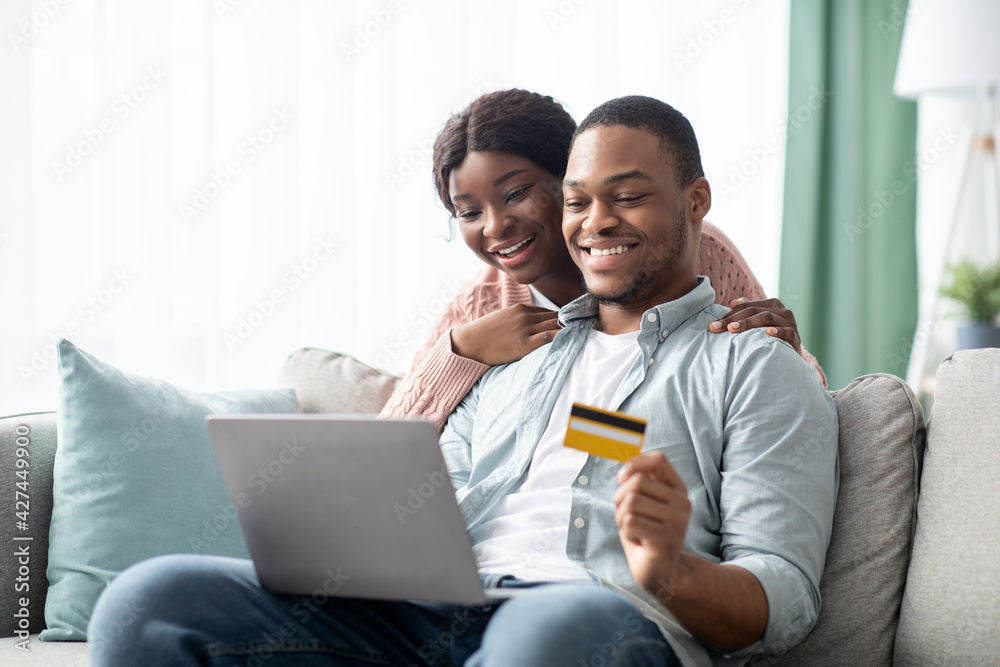 Cheerful young black man and woman shopping online, copy space Cheerful young black man and woman shopping online, copy space
