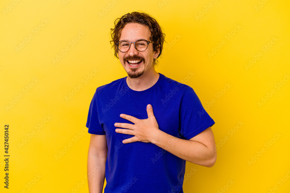 Young caucasian man isolated on yellow background laughs out loudly keeping hand on chest. Young caucasian man isolated on yellow background laughs out loudly keeping hand on chest.