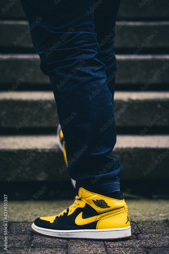 VANCOUVER, CANADA - Apr 12, 2021: Man in dark blue jeans wearing Jordan 1s  retro new love on cement in front of s Photos | Adobe Stock