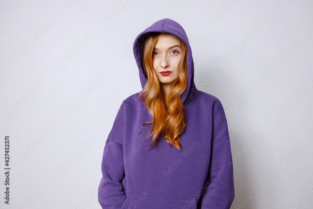 Portrait of a redhead woman in a purple hoodie and hood. White background Portrait of a redhead woman in a purple hoodie and hood. White background