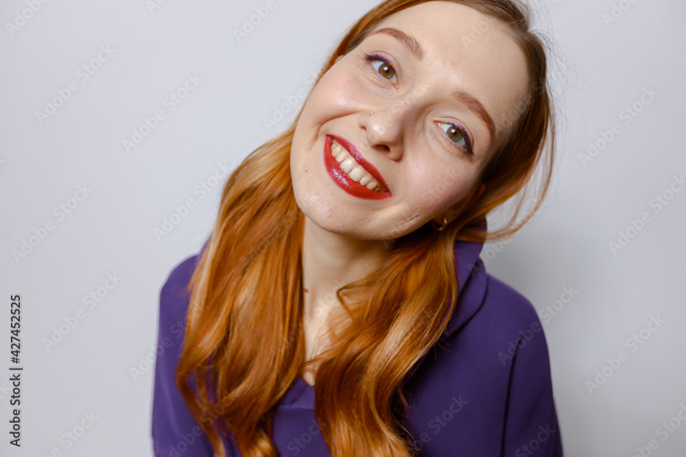Portrait of a smiling red-haired woman in a purple hood on a white background Portrait of a smiling red-haired woman in a purple hood on a white background