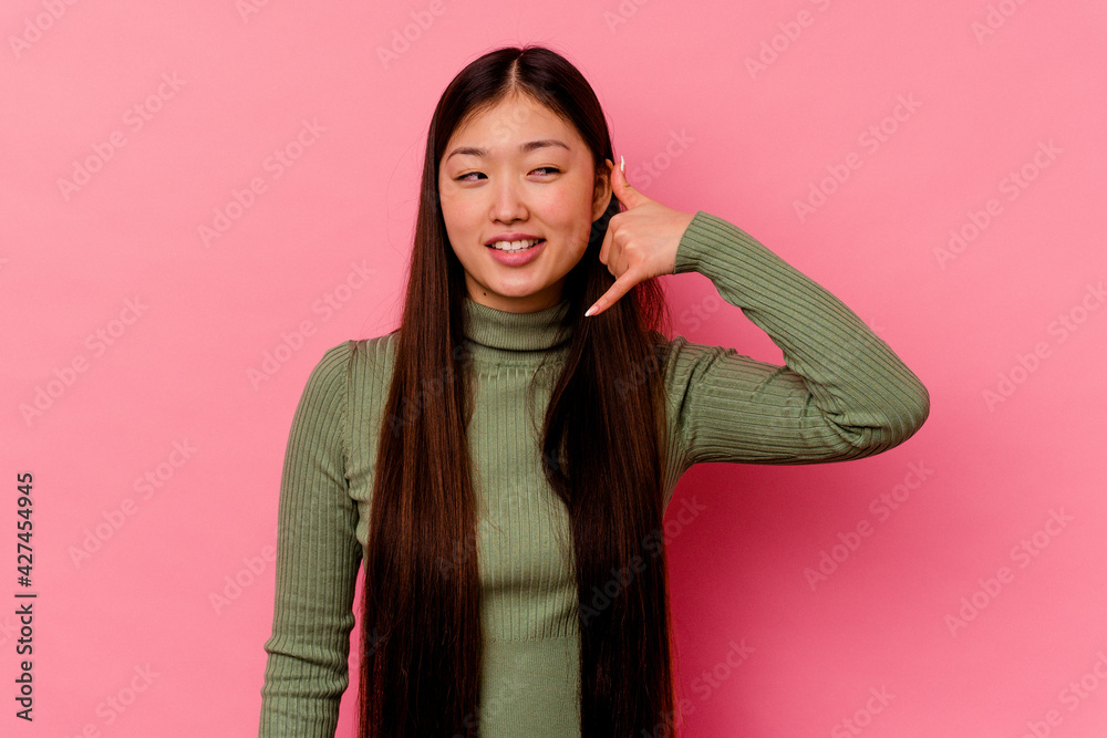 Young chinese woman isolated on pink background showing a mobile phone call gesture with fingers. Young chinese woman isolated on pink background showing a mobile phone call gesture with fingers.
