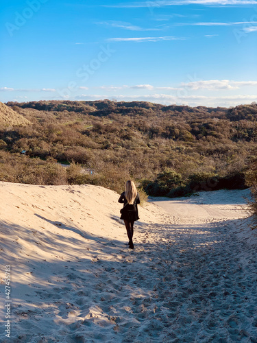 Girl walking through sand dunes at dusk at Westenschouwen, Schouwen-Duiveland