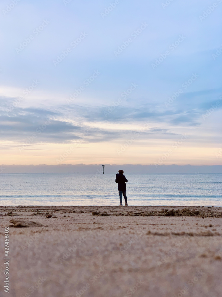 boy looking at the ocean at dusk on a serene, still water day
