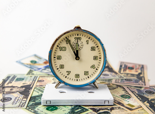 The old ruined blue analog clock is on a white audio music cassette, and below is cash. Everything is on a white background. Copy space. Music. Time. Money.