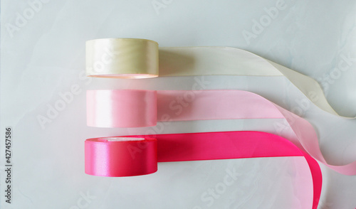 White, blush and pink silk ribbon rolls in white marble background © hippomyta