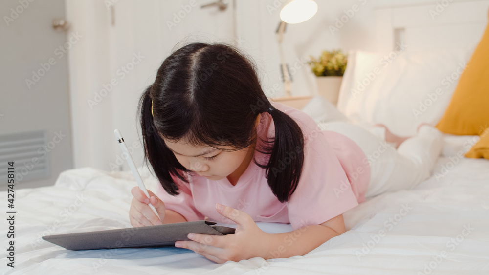 Young Asian girl drawing at home. Asia japanese woman child kid relax rest fun happy using tablet draw cartoon before sleep lying on bed, feel comfort and calm in bedroom at night concept. Young Asian girl drawing at home. Asia japanese woman child kid relax rest fun happy using tablet draw cartoon before sleep lying on bed, feel comfort and calm in bedroom at night concept.