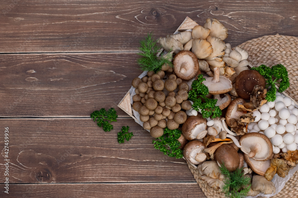 Variety of uncooked wild forest mushrooms in a wood box on wooden old board. Variety of uncooked wild forest mushrooms in a wood box on wooden old board.
