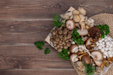Variety of uncooked wild forest mushrooms in a wood box on wooden old board.