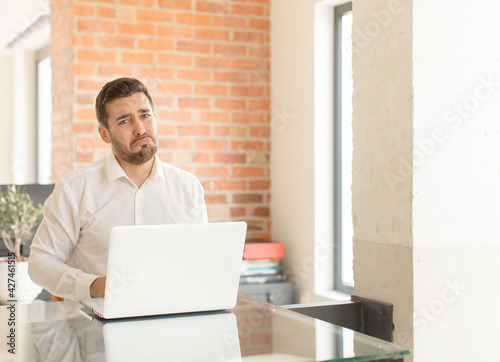 handsome businessman feeling sad and whiney with an unhappy look, crying with a negative and frustrated attitude photo