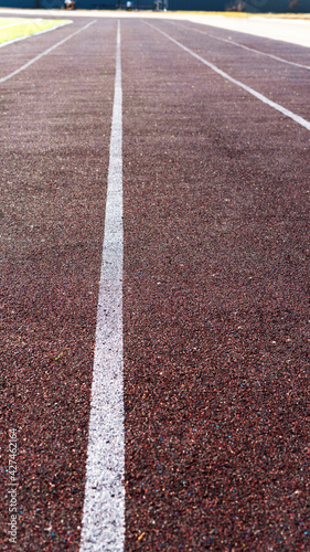 Running track in sports stadium. Red running or jogging race track rubber with white lines and texture. Empty running track background. Selective focus.