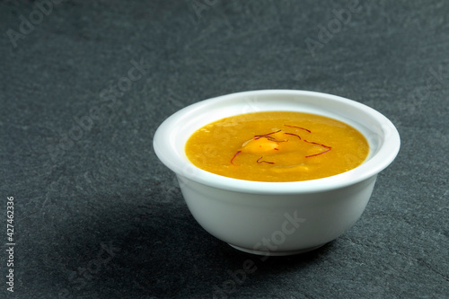 Aamras is plain Haapus or Alphonso Mango Puree/Pulp with kesar/ saffron topping. Aam Ras is a delicious Indian seasonal Dessert recipe. Served in a white bowl on white background