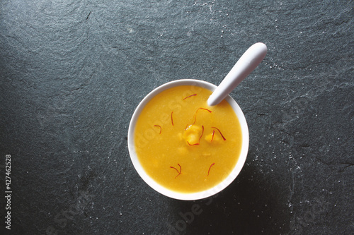 Aamras is plain Haapus or Alphonso Mango Puree/Pulp with kesar/ saffron topping. Aam Ras is a delicious Indian seasonal Dessert recipe. Served in a white bowl on white background photo