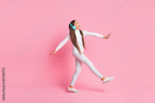 Full size profile photo of optimistic nice brunette girl go listen music wear sweater isolated on pink color background