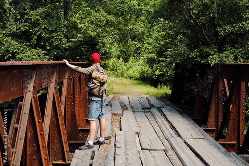 A man with a backpack on a wooden bridge against the backdrop of a beautiful mountain landscape with trees. Hike along the hiking trail. Travel and exploration. Healthy lifestyle  active rest