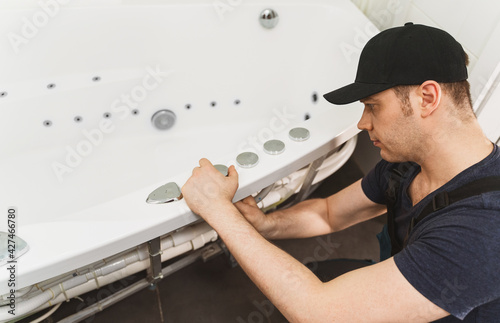 Man installing pipe system of bathtub with hydromassage.