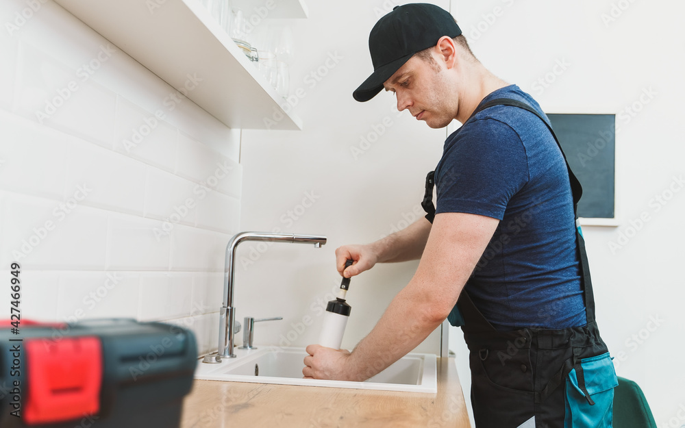 Plumber unclogging kitchen sink with professional force pump cleaner. Plumber unclogging kitchen sink with professional force pump cleaner.