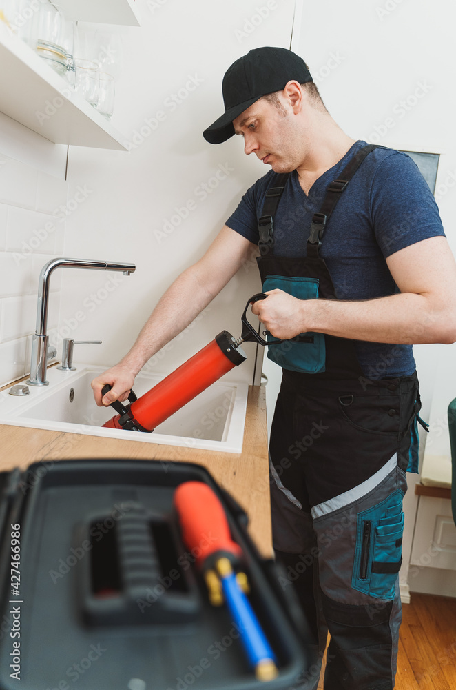 Plumber unclogging kitchen sink with professional force pump cleaner.