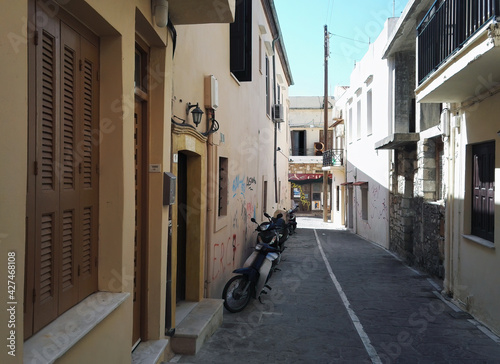 Crete  Greece  Narrow passage lane in between building with windows and two wheeler parked next to wall