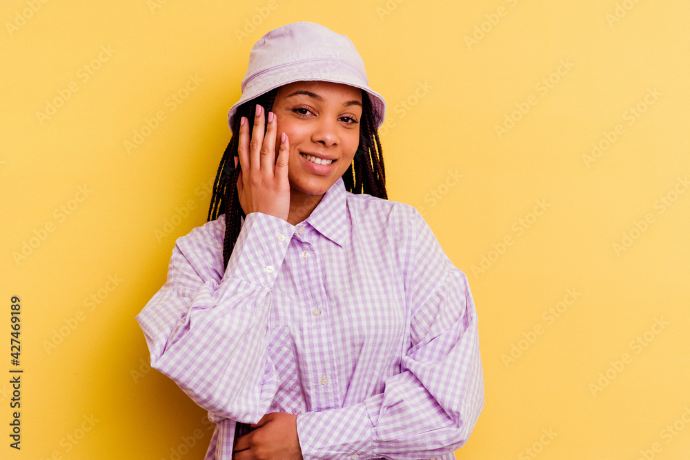 Young african american woman isolated on yellow background laughs happily and has fun keeping hands on stomach.