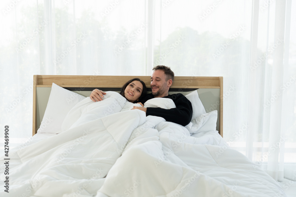 Fototapeta premium happy caucasian couple lying in the bed in bedroom at home in the morning