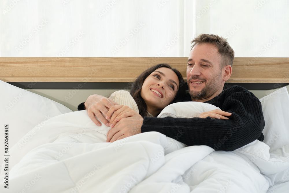 happy caucasian couple lying in the bed in bedroom at home in the morning