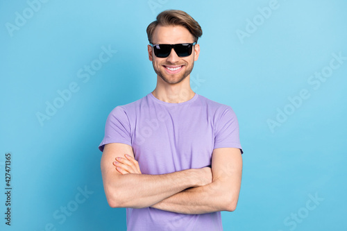 Photo of satisfied young man folded arms toothy smile wear violet outfit isolated on blue color background