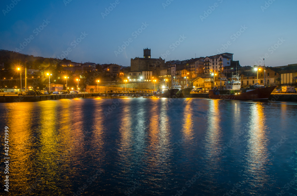 Dusk in Guetaria, Spain, from the sea. reflections of lights in the water