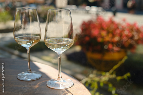 Two glasses of white wine in the sun on a table in a restaurant. Summer holiday. Celebrate and enjoy moment. Alcoholic drink tasting. Romantic evening aperitif. Wine glass close up