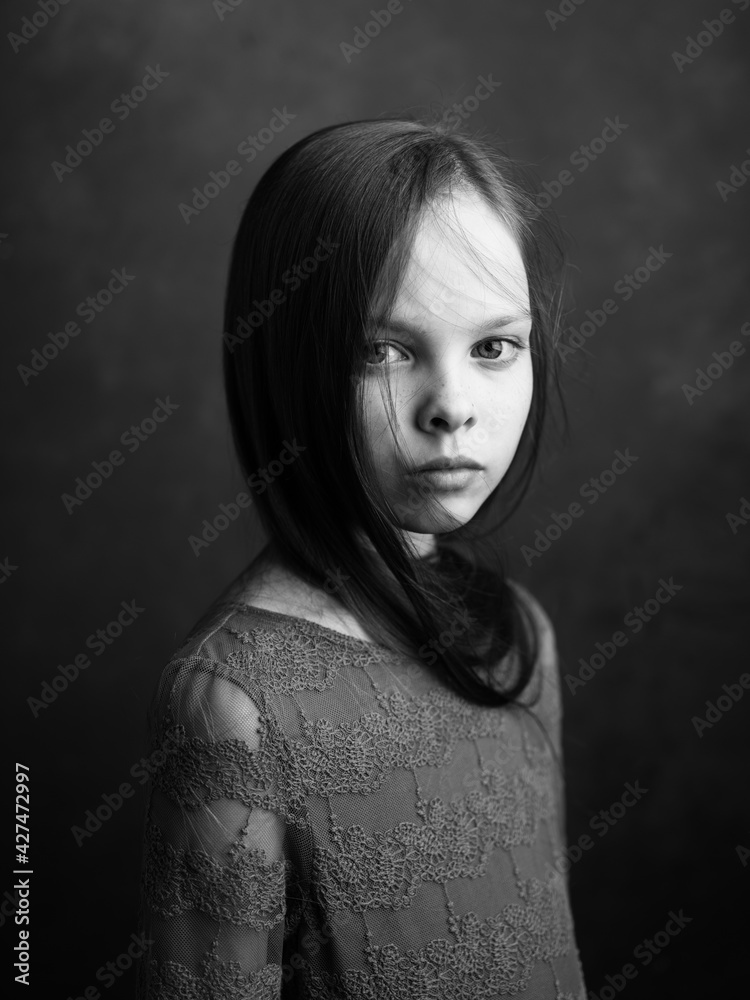 Portrait of a little girl in a dress on a dark gray background photograph cropped side view