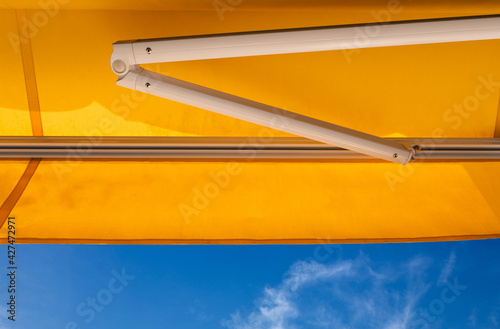 yellow awning canvas against bluesky. exterior shading roof.