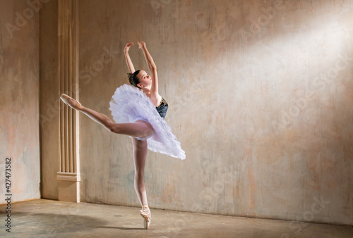Young ballerina in white tutu dancing in a spotlight in vintage scene
