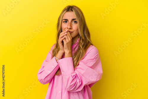 Young blonde caucasian woman isolated on yellow background scared and afraid.