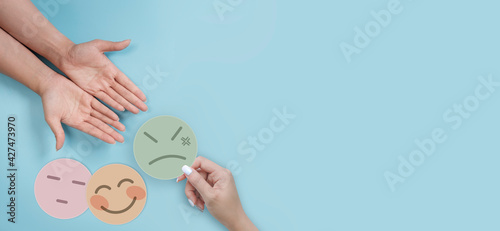 Woman hand choosing angry face paper cut to another people, feedback rating and negative customer review, experience, satisfaction survey ,mental health assessment, world mental health day concept 