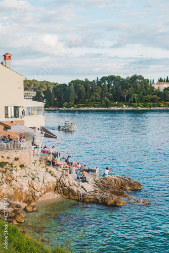 Rovinj, Croatia - May 30, 2019: people sitting in cafe at sea beach photo