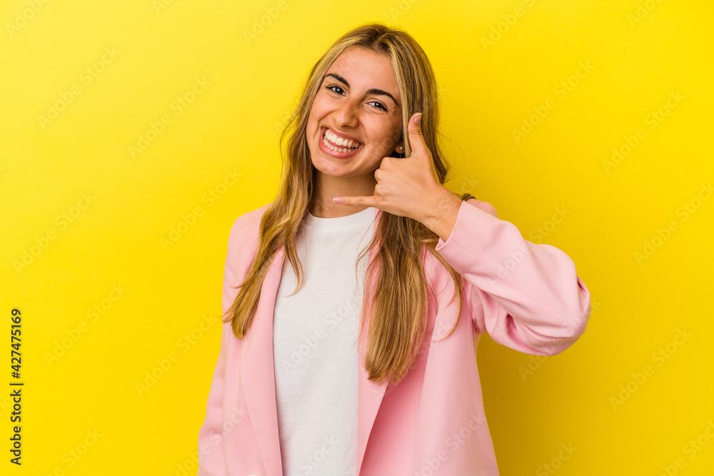 Young blonde caucasian woman isolated on yellow background showing a mobile phone call gesture with fingers. Young blonde caucasian woman isolated on yellow background showing a mobile phone call gesture with fingers.