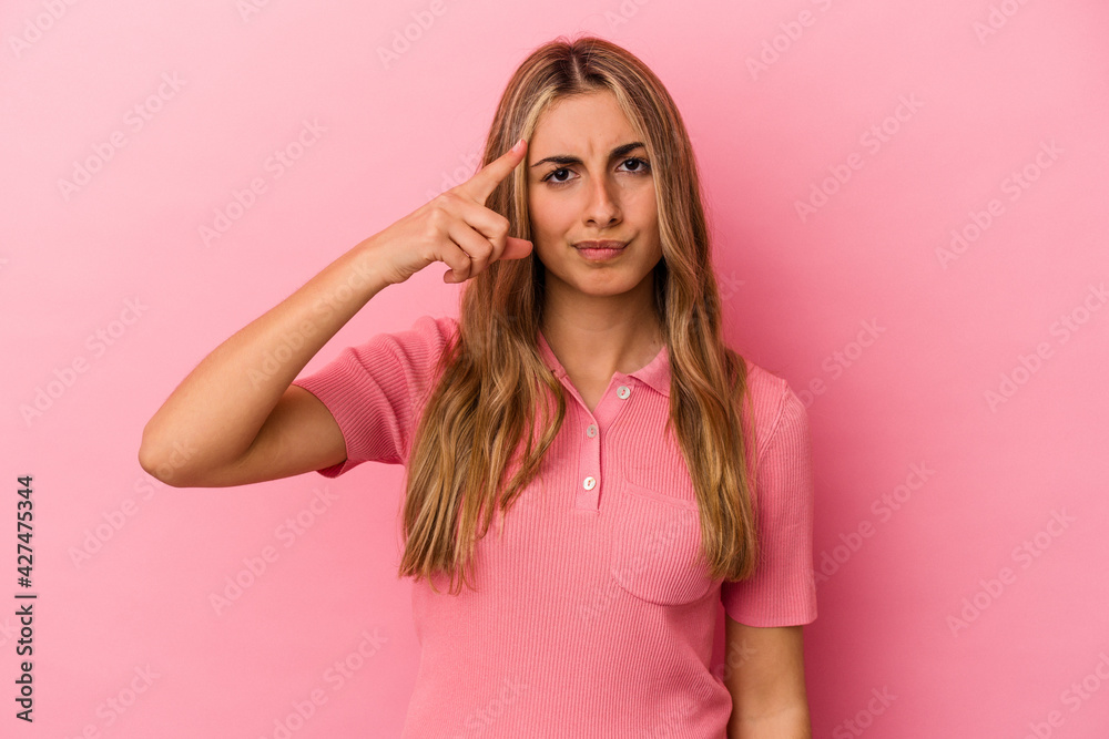 Young blonde caucasian woman isolated on pink background pointing temple with finger, thinking, focused on a task. Young blonde caucasian woman isolated on pink background pointing temple with finger, thinking, focused on a task.