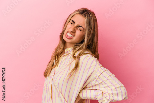 Young blonde caucasian woman isolated on pink background suffering a back pain. © Asier