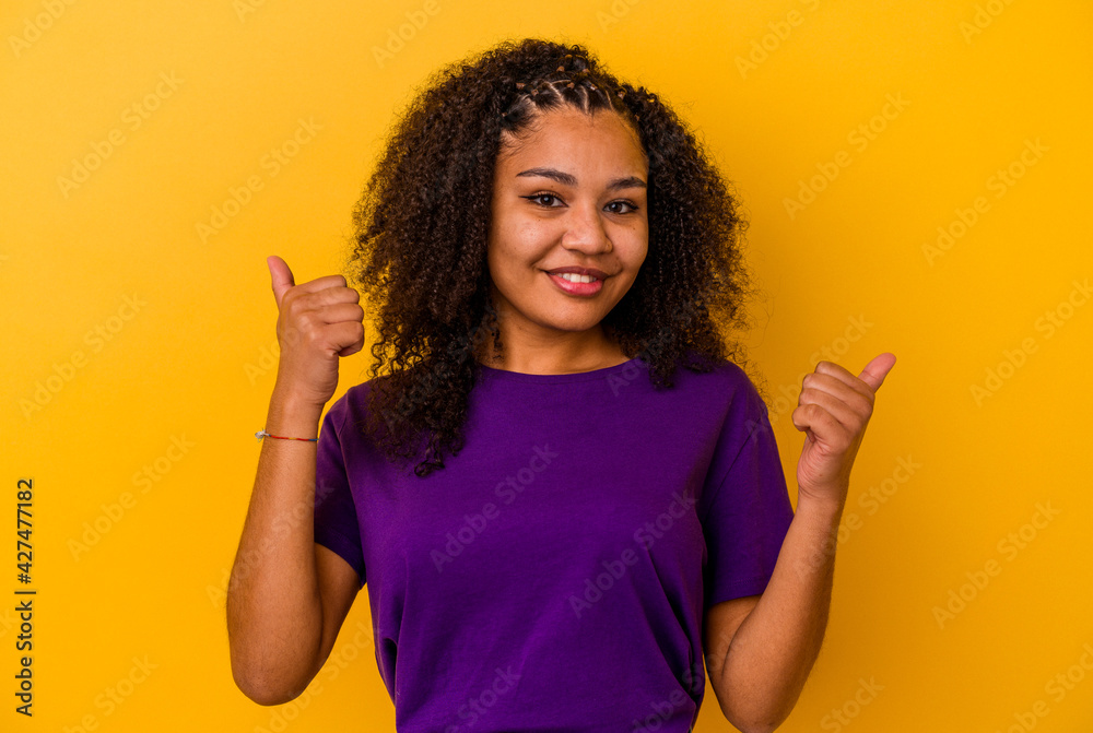 Young african american woman isolated on yellow background raising both thumbs up, smiling and confident. Young african american woman isolated on yellow background raising both thumbs up, smiling and confident.