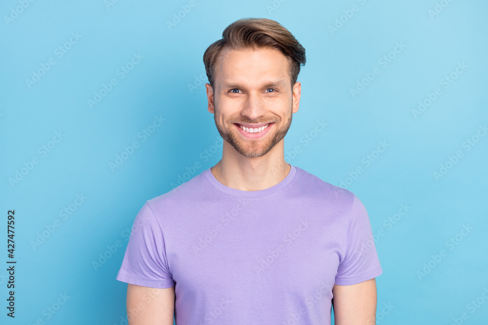 Photo portrait of smiling guy wearing purple t-shirt isolated on pastel blue color background Photo portrait of smiling guy wearing purple t-shirt isolated on pastel blue color background
