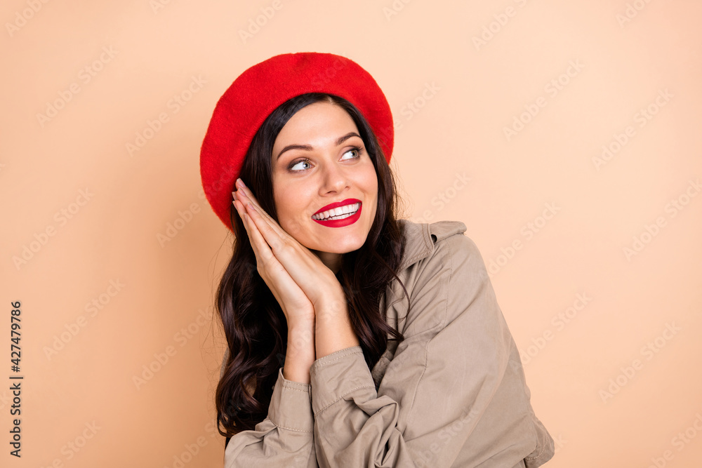 Photo portrait of cute girl holding hands together looking at blank space isolated on pastel beige colored background Photo portrait of cute girl holding hands together looking at blank space isolated on pastel beige colored background