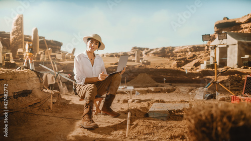 Archeological Digging Site Discivery: Beautiful Female Archaeologist Doing Research, Using Laptop, Analysing Unearthed Ancient Civilization Culture Artifacts. Great Historian on Excavation Site