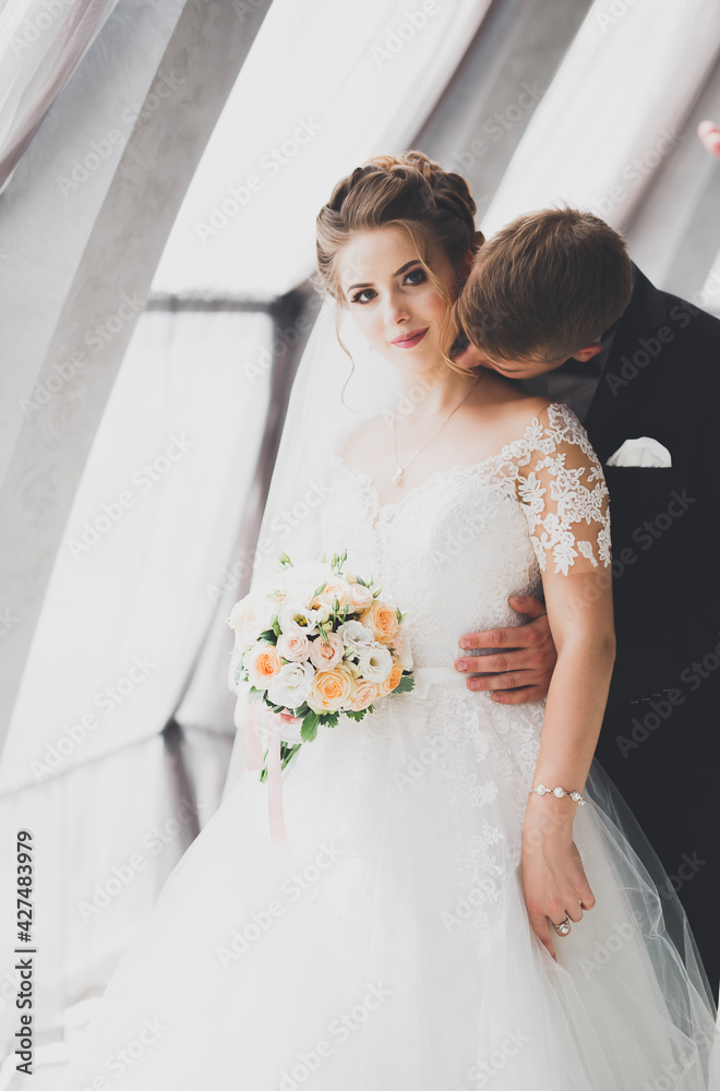 Lovely happy wedding couple, bride with long white dress posing in beautiful city Lovely happy wedding couple, bride with long white dress posing in beautiful city