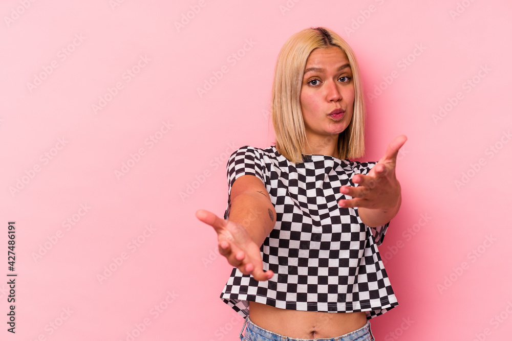 Young venezuelan woman isolated on pink background folding lips and holding palms to send air kiss. Young venezuelan woman isolated on pink background folding lips and holding palms to send air kiss.