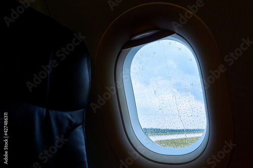 The interior of a passenger plane before takeoff. Porthole in raindrops