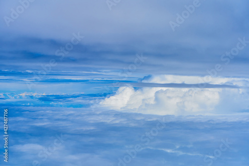 Landscape of fluffy white clouds on a dark blue sky. View from the plane at high altitude