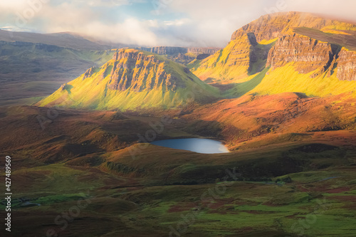 Fototapeta Naklejka Na Ścianę i Meble -  Vibrant golden light over epic mountain landscape of the rugged, contoured terrain of the Cleat and Dun Dubh at the Quiraing on the Isle of Skye, Scotland.